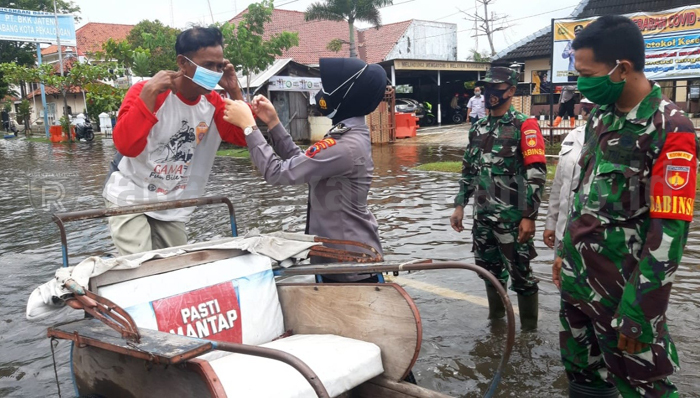 Petugas Gabungan Bagikan Masker di Tengah Banjir